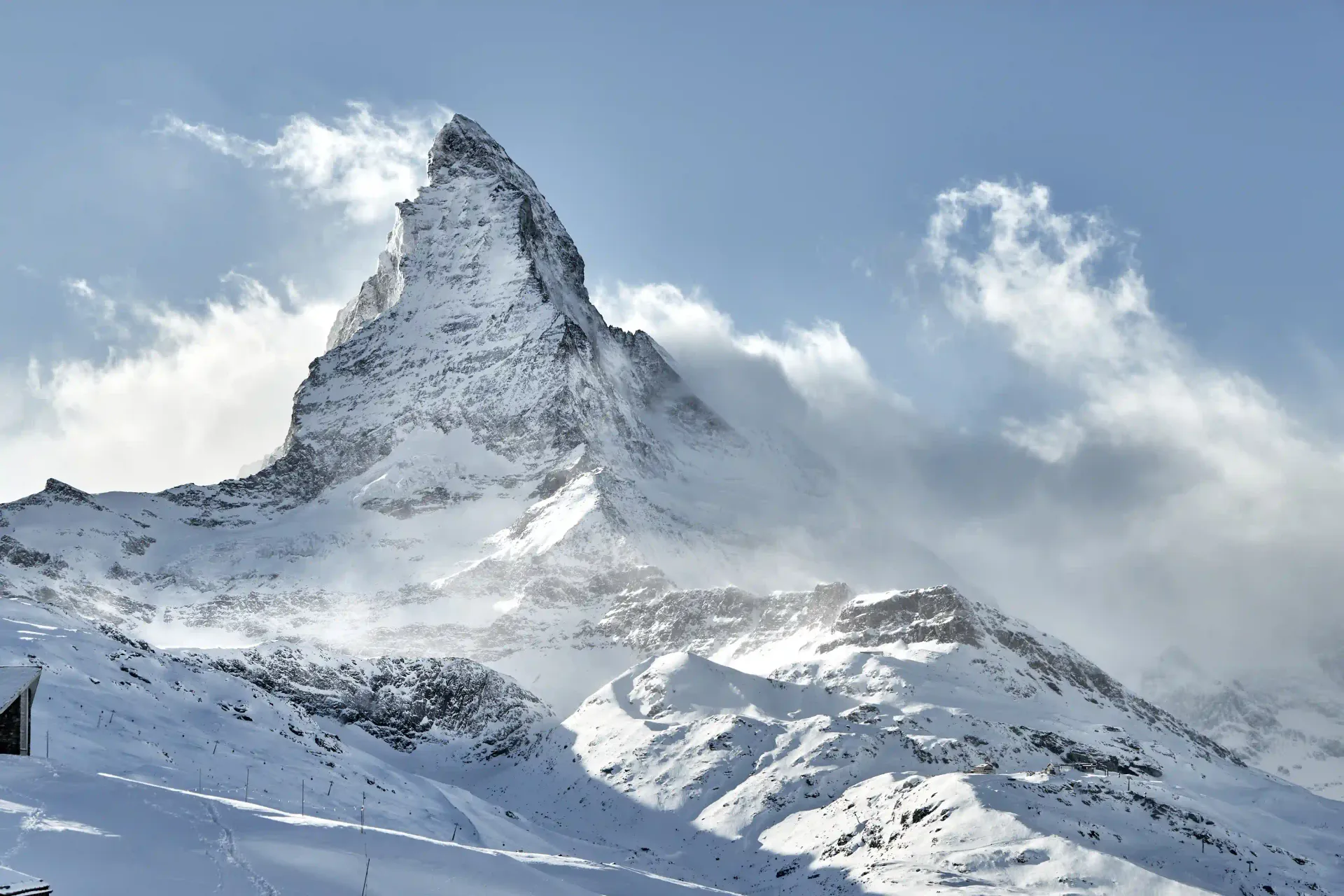 Vue majestueuse du Cervin enneigé sous un ciel bleu partiellement nuageux.