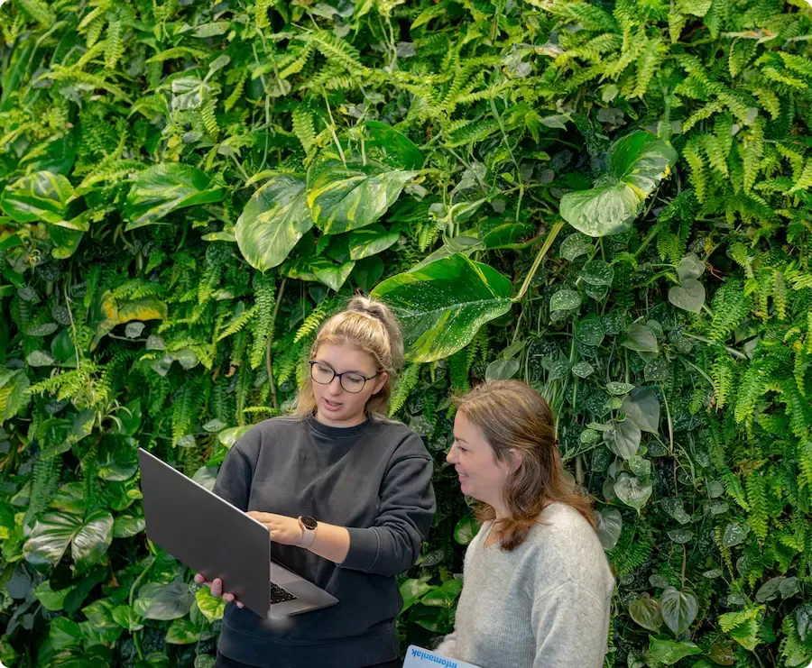 Image de deux employées devant un mur végétal