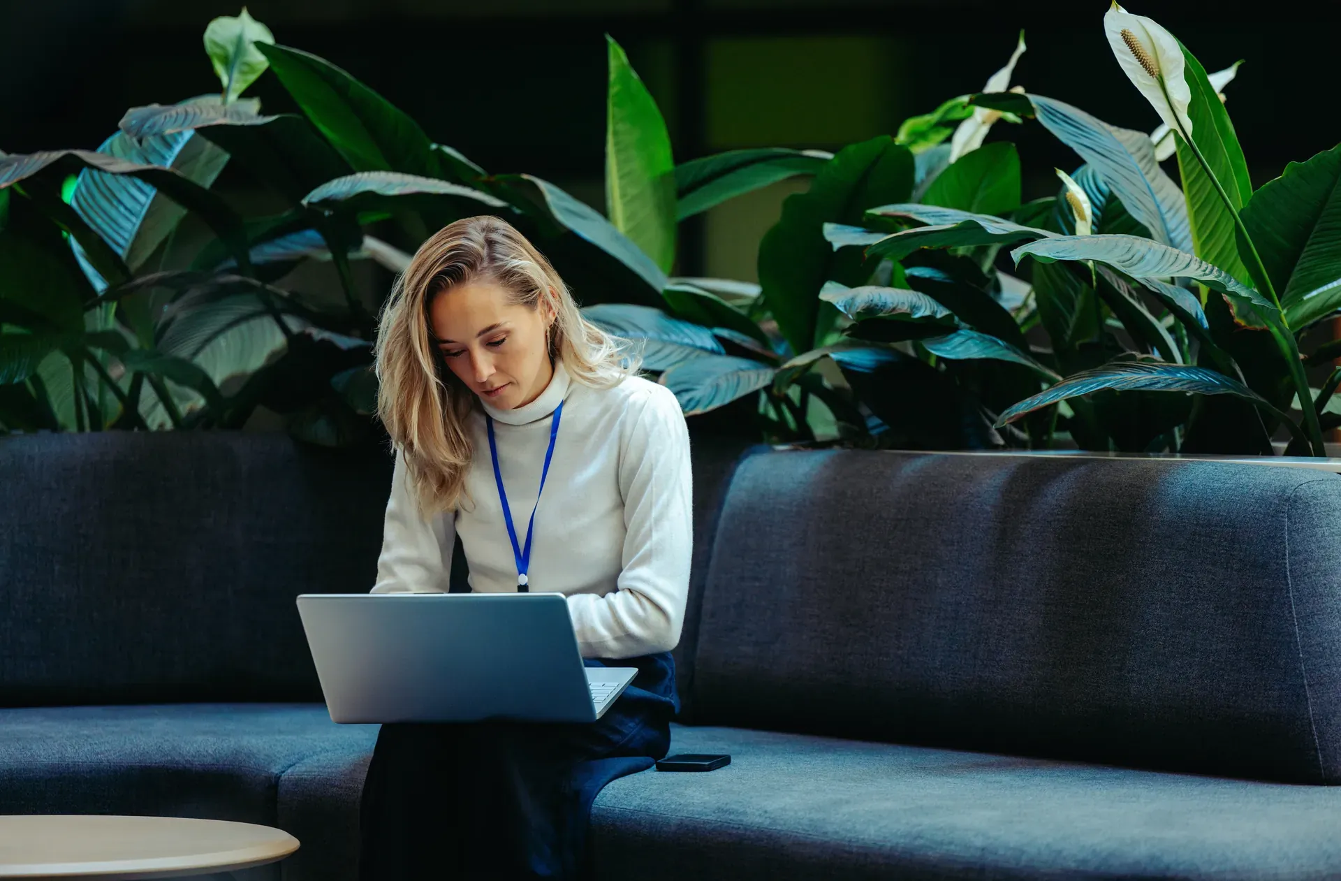 Femme assise sur un canapé qui consulte un pc portable